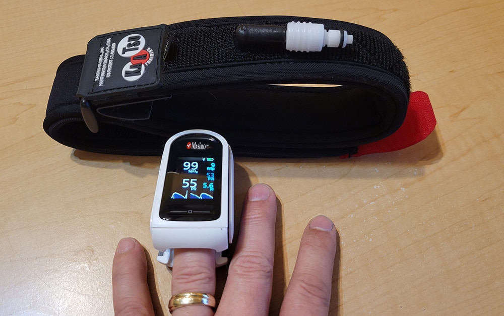 KAATSU Air Band near hand with Masimo MightySat pulse oximeter on ring finger.